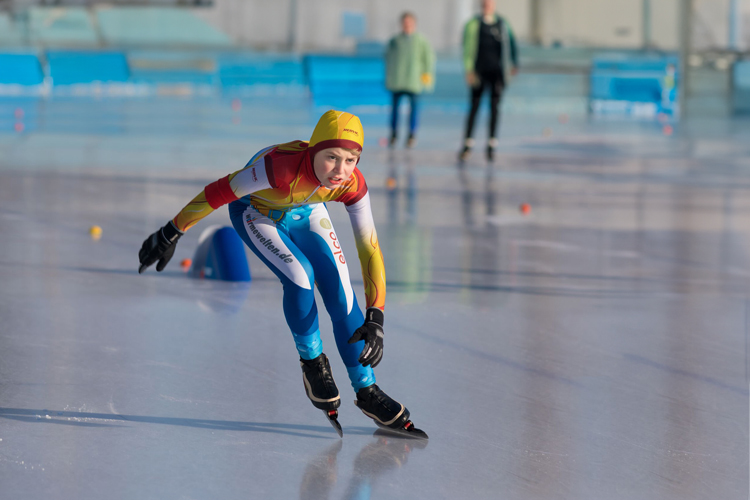Boy with colourful suit skates on the ice