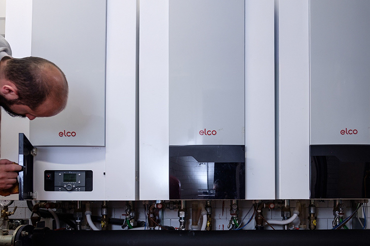 A man looks into the control element of an ELCO heating system.